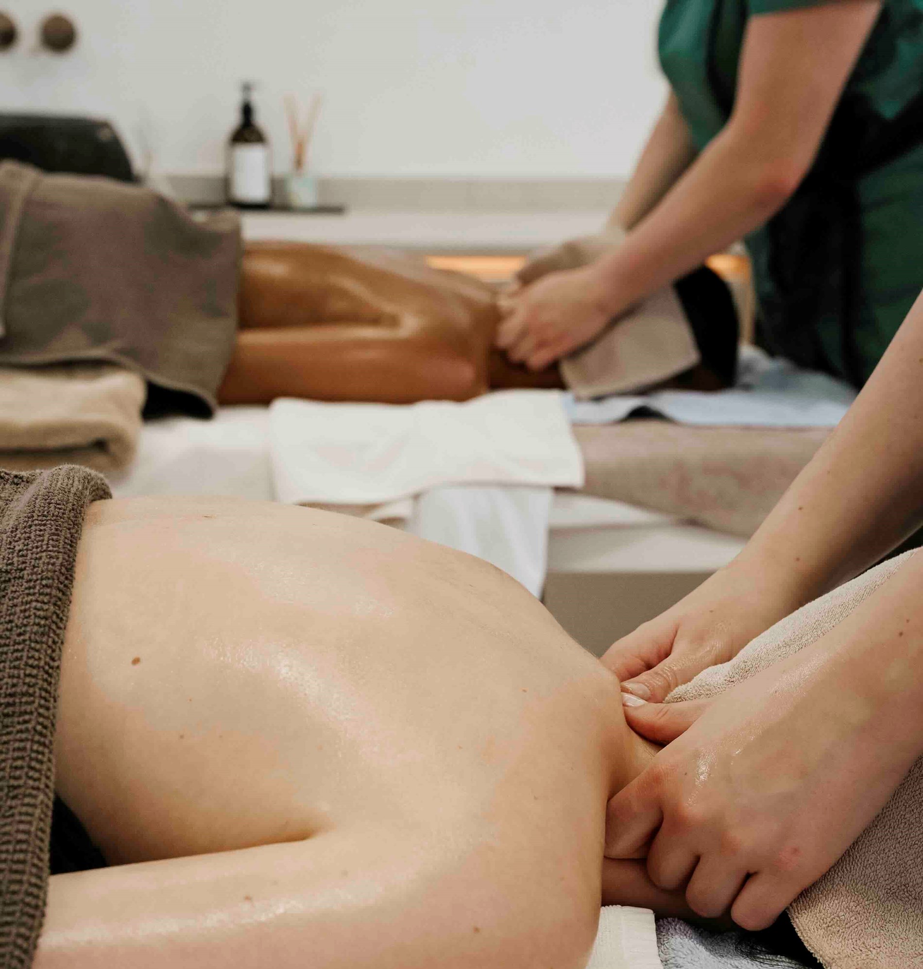 Zwei Gäste bei Paarmassage nebeneinander auf Massageliegen